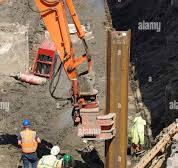 Hydraulic sheet steel pile driver attached to excavator arm ...