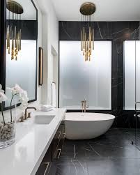 Black And Gold Marble Bathroom Tiles The Litze Bath Collection In Brilliance Luxe Gold And A Bold Chandelier Accent Luxurious Blac White Marble Bathrooms White Bathroom Tiles Black Marble Bathroom