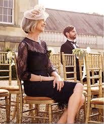 Mother Of The Bride Wearing Black Lace Dress And Cream Fascinator Sat With Wed Lace Wedding Guest Dress Mother Of The Bride Outfit Mother Of The Bride Fashion