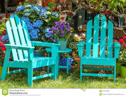 Two Turquoise Adirondack Chairs And A Matching Table Surrounded By Beautiful Flowers And Trees And Shining Mirr Garden Furniture Garden Chairs Green Wood Stain