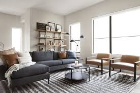 Minimal Midcentury Living Room Featuring A Dark Gray Sectional Round Metal Coffee Tab Grey Sofa Living Room Dark Grey Sofa Living Room Grey Couch Living Room
