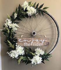 Diy Bicycle Wreath With Enjoy The Ride Sign Using Artificial Floral And An Old Bike Wheel Bike Decorations Bicycle Decor Bicycle Wheel Decor