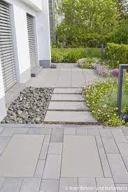 Der Ubergang Von Eingangsbereich Zu Terrasse Wird Mit Passenden Betonplatten In Rindenmulch Ge Ummauerter Garten Abschussiger Garten Kleiner Hof Landschaftsbau