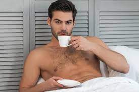 Nackter gutaussehender mann, der im bett kaffee trinkt und in die kamera  schaut | Premium-Foto
