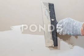 Man Plastering Wall With Putty Knife