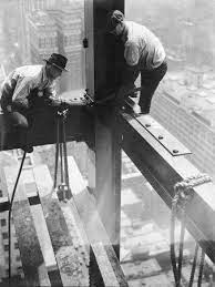 workers balancing on steel beam above