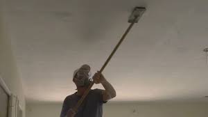 A Drywall Worker Sanding A Ceiling At A