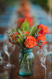 Simple Centerpieces With Blue Mason Jars Coral Roses Greenery Mason Jar Flower Arrangements Mason Jar Flowers Wedding Centerpieces Mason Jars