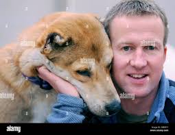 Former Royal Marine Penny Farthing with Bear, 1, a puppy who was rescued  from dog fighting in Afghanistan, during his arrival to the Mayhew Animal  Home in north west London Stock Photo -
