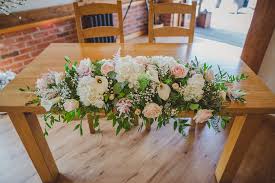 We would like to show you a description here but the site won't allow us. The Ceremony Table Was Decorated With An Arrangement Of Delicate Pale Pink And White Wedding Flowers And Lush Green Foliage Sandhole Oak Barn