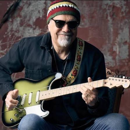 Greg Koch seated with his seafoam Telecaster against a teal studio backdrop