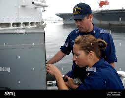 U.S. Coast Guard Chief Electronics Technician Keith Ayotte watches as  Electronics Technician 1st Class Jeannette Whitney performs routine  maintenance