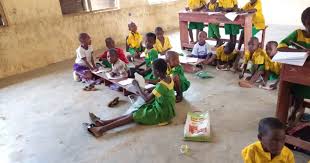 Pupils in Ebonyi State community primary school learning in a classroom with unfinished block walls, no furniture and bare concrete floors