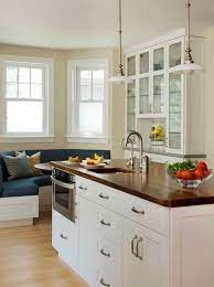 A pair of altamont pendants hang over a dark brown kitchen island with x panel trim on each end atop dark stained oak wood floors. Brown Quartz Countertop With White Cabinetry Kitchen Design Kitchen Redesign Kitchen Cabinet Design
