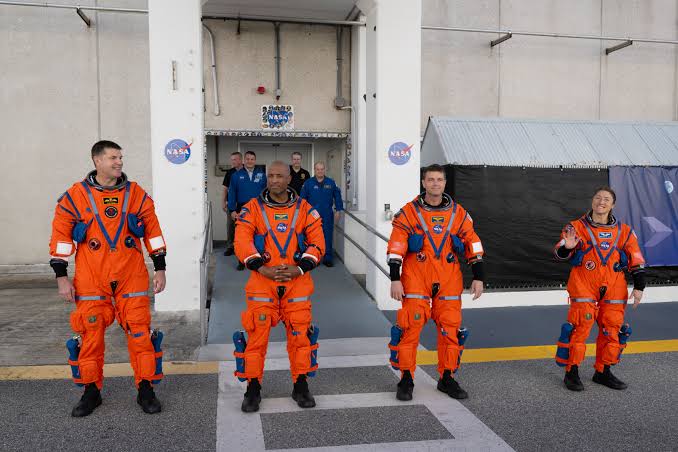 The Artemis II crew in orange flight suits during pre-mission preparations