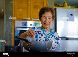 lifestyle portrait of senior happy and sweet Asian Japanese retired, woman  cooking at home kitchen alone neat and tidy enjoying preparing meal in elde  Stock Photo - Alamy
