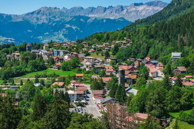 Vue panoramique de Saint-Gervais-les-Bains avec ses chalets, son église et les montagnes du massif du Mont-Blanc en arrière-plan.