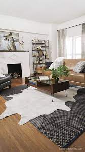 A Living Room Space With A Faux Cowhide Rug Art Nouveau Fireplace And Touches Of Gold Rugs In Living Room Layered Rugs Living Room Cowhide Rug Living Room
