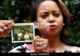 In this Sept. 6, 2019, photo, Donna Cryer holds up family photos that  include her father Roland Henry, as she poses for a photo in Washington.  When her father died, she tried