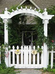 A brick pathway with colorful flowers on each side creates an inviting look in the small space. Front Gate Arbor Gate Arbor Garden Gate Design Trellis Gate