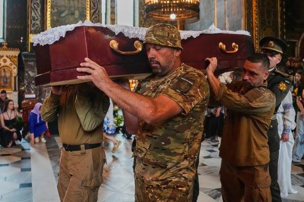 Mourners and fellow volunteers pay their respects at the funeral of Oleksiy Yukov.