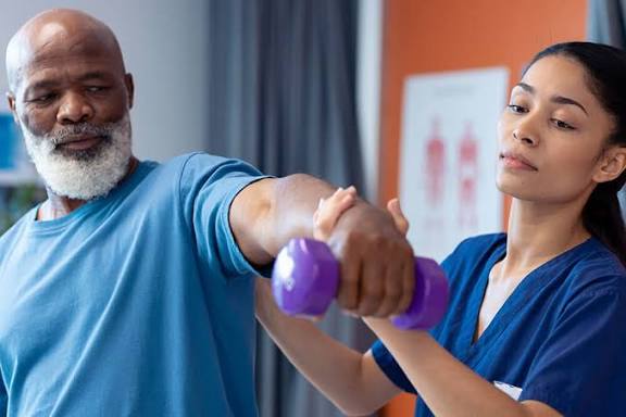 Therapist supporting a patient lifting a small dumbbell