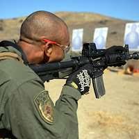Lt. Cmdr. Brendan Gray, maintenance officer from the Shadowhawks of  Electronic Attack Squadron (VAQ) 141, fires a 9mm pistol during a live-fire  exercise aboard the Nimitz-class aircraft carrier USS George Washington (CVN