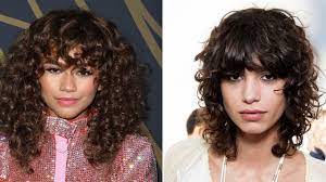 Wavy curly hair is left long and cut to form side swept fringe. Tips For Great Bangs With Curly Hair Allure