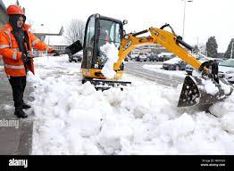 A workman and a JCB machine clearing the snow in Denny, Scotland Stock  Photo - Alamy
