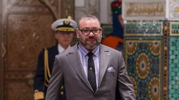 King Mohammed VI of Morocco standing in a formal setting.