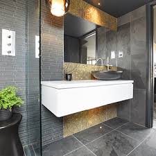 The rough brick wall and unfinished wood table of this space contrast with the smooth, geometrical look of the washbasin and mirror. Bathroomsbydesign Nationwide Bathroom Design Specialists