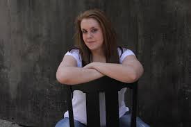 senior girl sitting backwards on a chair with arms crossed and head slightly turned senior girls senior girl poses girl poses