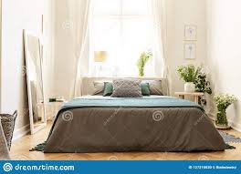 Blanc et gris clair pour optimiser la luminosité d'une pièce. Interieur Beige Vert Et Gris De Chambre A Coucher Dans Une Maison D Appartement Avec Un Lit Contre Une Fenetre Ensoleillee Et De Photo Stock Image Du Maison Home 127216030