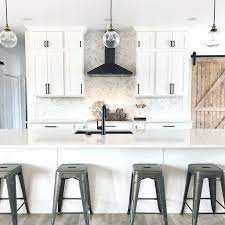 Countertops are white granite with spots of blue and have white subway tile backsplash. Best Sherwin Williams White For Cabinets