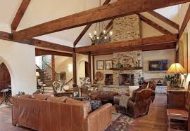 Stone walls, rustic wooden coffee table with two chairs on each side providing seating for four people. Living Rooms With Beams That Will Inspire