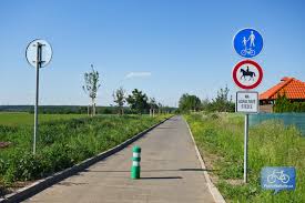 Znak tvoří modrý štít v dolní části vyplněn půdou písčité barvy, se stříbrnými městskými hradbami s cimbuřím, z nichž vystupují dvě věže s červenou střechou a s okny se zlatými mřížemi. Cyklotrasa A50 Uhrineves Kralovice Stupice Kolodeje Ujezd Nad Lesy Klanovice Praha Na Kole