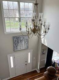 Sherwin Williams AGreeable Gray in two storey foyer with high ceilings and white front door warm orange toned wood flooring