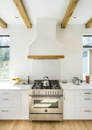These stove hoods are affordable and easy to install. Bright White Cabinetry And Range Hood Surrounding Stainless Steel Stove Under Natural Wood Exposed Beams Hgtv