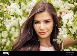 Romantic woman with perfect windy brown hair in spring flowers garden Stock  Photo