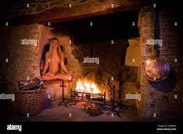 Beautiful nude young blonde haired woman sitting in the alcove of an  ancient inglenook fireplace. JMH4995 Stock Photo - Alamy