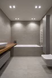 A grey concrete bathroom with pavement tiles and gravel on the floor plus gold fixtures to add chic to the space. 25 Trendy Grey Bathroom Designs Digsdigs