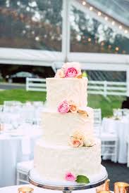 Classic White Wedding Cake With Pops Of Pink Flowers The White Clear Tent Makes For A Stunning Background Photo Organic Cake White Wedding Cake Wedding Cakes
