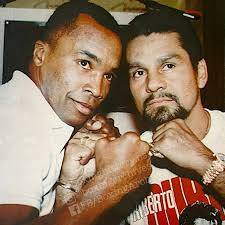 Heavyweight greats "Smokin'" Joe Frazier and Muhammad Ali gesture at one  another past former heavyweight champion Joe Louis ahead of their third  fight, the "Thrilla in Manila," for the heavyweight championship in