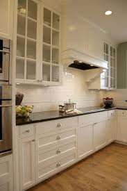 Black granite countertop, cooker, and range hood add drama to the kitchenette. The Classic Beauty Of Subway Tile Backsplash In The Kitchen