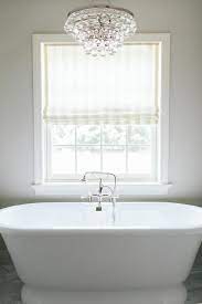 It makes the bathroom look less like a bathroom, somehow, and a little more like a place where you'd want to spend a bunch of time reading and drinking and soaking away the day. Robert Abbey Bling Chandelier Over Tub Transitional Bathroom Trendy Bathroom Bathroom Chandelier Chandelier Over Tub