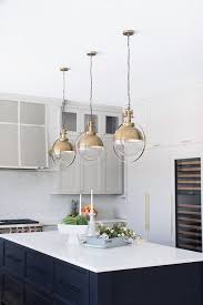 brass lights over black shiplap island