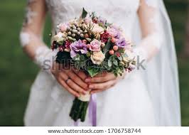 Fresh pink roses, lovely orchids, and green berries get an added touch of sparkle with a jeweled pin. Shutterstock Puzzlepix