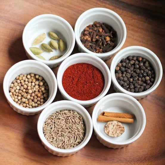 Close-up of traditional Machboos spices including cardamom, cinnamon, cloves, black lime, and turmeric