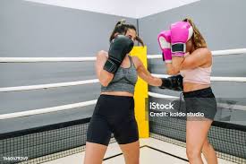 Boxer Giving A Low Blow To Her Colleague Who Are Practicing In The Ring  Stock Photo - Download Image Now - iStock