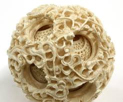 The stand has a mythical creature carved around the base and piercing within. Chinese Ivory Puzzle Ball Elephant Stand